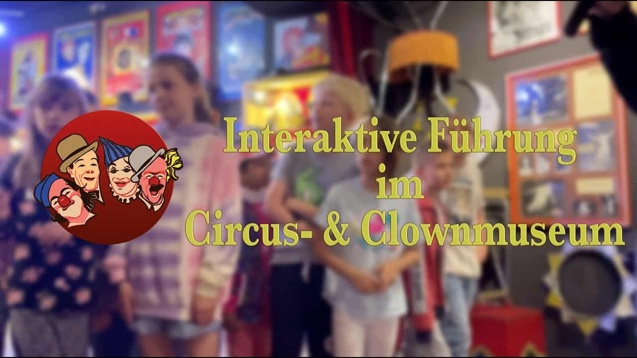 Vier lächelnde Mädchen halten einen riesigen Clownschuh bei den Kindergarten- und Schulführungen im Circus- & Clownmuseum Wien.